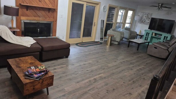 Un saló amb un sofà marró, una taula de centre de fusta amb llibres, un televisor i un balcó amb barana.