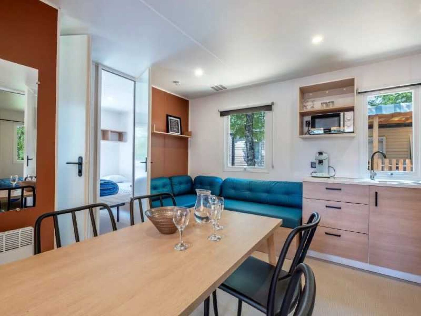 A compact living space with a dining area, kitchenette, and a blue sofa.