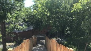 A wooden pathway leading to a traditional building with a tiled roof, surrounded by trees. - ZEcamping 3* piscine chauffée hammam sauna mobil-home TV LV 49m2 (Verruyes)