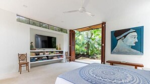 A bedroom with a bed, a TV, a bookshelf, and a painting. - Yeguas V60 by Wynwood House (Anapoima)