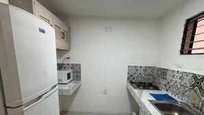 A compact kitchen with a refrigerator, microwave, and sink.