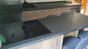 Una cocina con encimera negra, estufa integrada y armarios de madera.