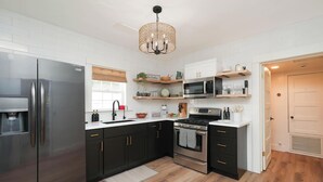 Una cocina moderna con muebles oscuros, electrodomésticos de acero inoxidable y una isla central.