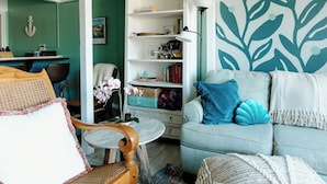 A cozy living room with a light blue sofa, a wooden chair, a small round table, and a bookshelf.