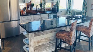 A modern kitchen with a central island, stainless steel appliances, and a stone backsplash.
