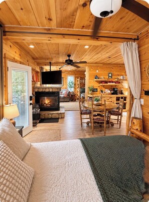 Ein gemütliches Blockhauss-Interieur mit Kamin, Holzmöbeln und einer Essecke.