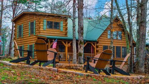 A log cabin with a porch and two Adirondack chairs.