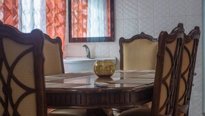 A dining table with a golden bowl, surrounded by chairs with intricate backs. - Afranasa Inn (Tema)