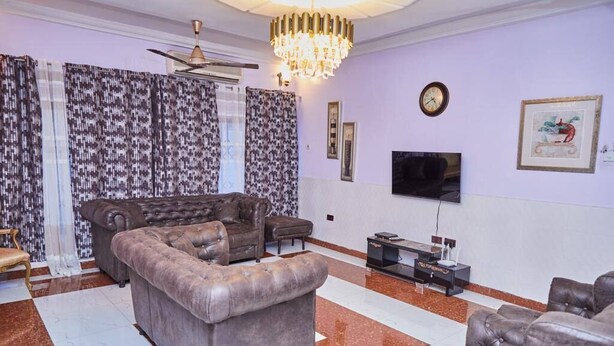 A living room with a sectional sofa, a TV, and a chandelier. - Afranasa Inn (Tema)