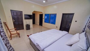 A bedroom with a bed, a TV, a chair, and a window. - Afranasa Inn (Tema)