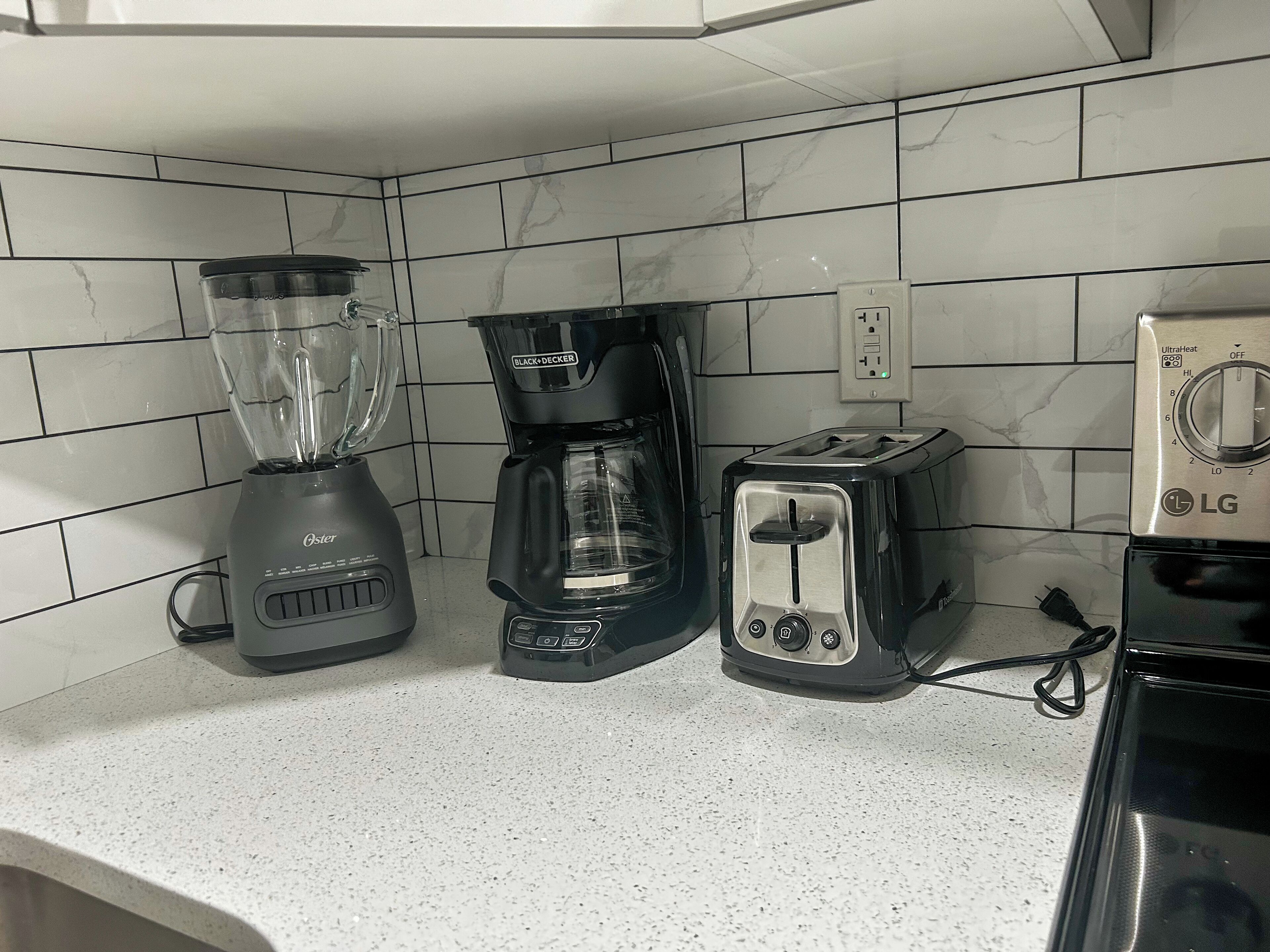 A kitchen with a blender, coffee maker, and toaster on the counter.