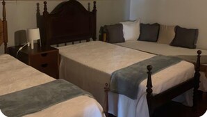 Una habitación con dos camas individuales, cada una con cabecero de madera y una mesita de noche con lámpara.