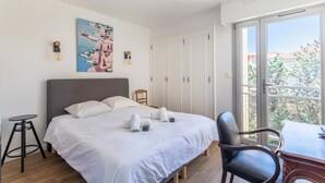Un dormitorio moderno con una cama grande, un escritorio y vistas a la ciudad a través de amplios ventanales.