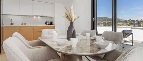 A modern dining area with a round table, six chairs, and a vase with dried plants.