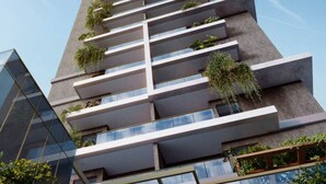 A modern high-rise building with multiple balconies, large windows, and greenery.