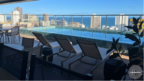 A rooftop pool area with lounge chairs and a city view.