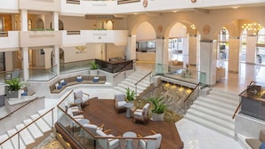 A spacious, multi-level hotel lobby with a central seating area, multiple staircases, and a decorative water feature. - Ocean front 2 bedroom Deluxe Suite at Villa Del Palmar Resort Cabo San Lucas (Cabo San Lucas)