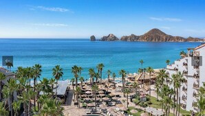 A resort with a pool area, palm trees, and a view of the ocean. - Ocean front 2 bedroom Deluxe Suite at Villa Del Palmar Resort Cabo San Lucas (Cabo San Lucas)