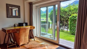 A room with a desk, chair, and a large sliding glass door leading to a balcony with a mountain view. - Residence Alpin TOP 1 Incl Summer Card (Kaprun)