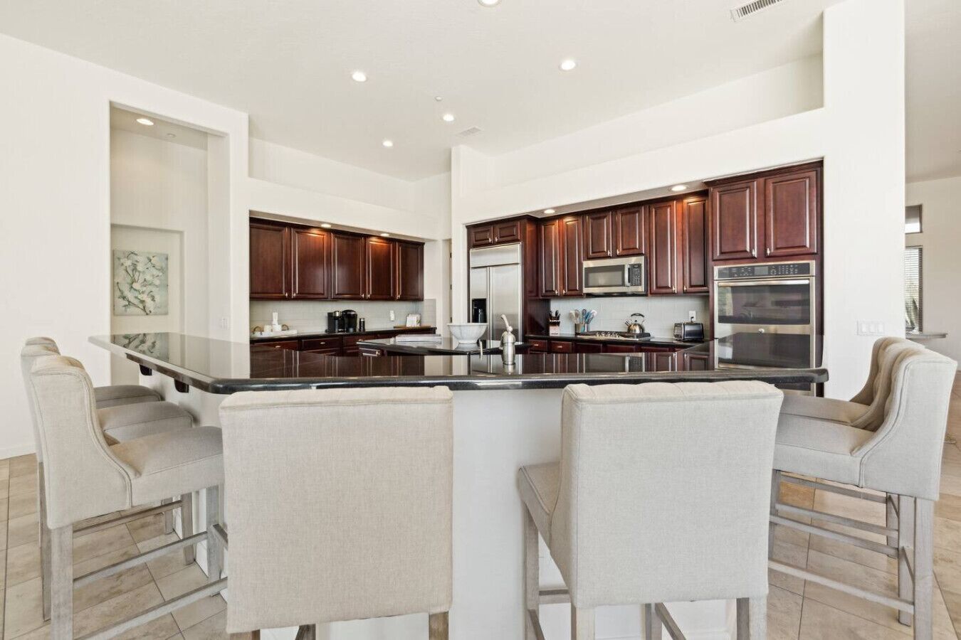 A modern kitchen with dark wooden cabinets, stainless steel appliances, and a central island with bar stools.