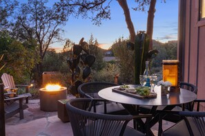 An outdoor patio with a round table, chairs, a fire pit, and a view of the sunset. - Redscape, Near Great Hiking, Views, Hot Tub, Firepit-Charming Design (Sedona)