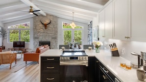 A spacious kitchen with a large island, stone wall, and a ceiling fan. - Redscape, Near Great Hiking, Views, Hot Tub, Firepit-Charming Design (Sedona)