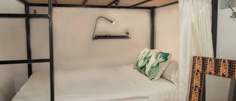 A bunk bed room with a small shelf and a lamp.