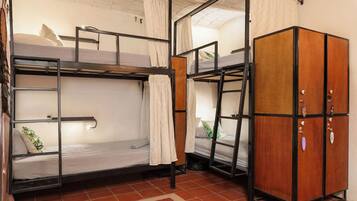 A dormitory room with bunk beds, a wardrobe, and a red rug.