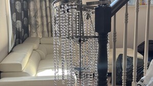 A staircase with a black balustrade, a beige sofa, and a chandelier with crystal decorations. - Spacious 4/bedroom house in delightfulneighborhood (Corona)