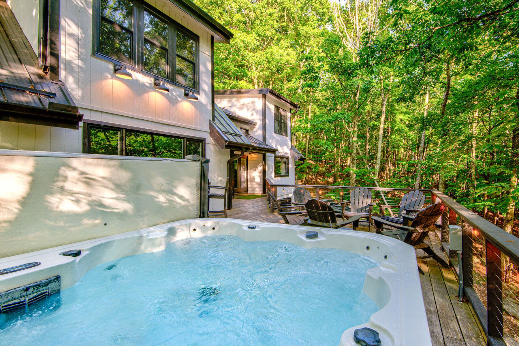 Un bain à remous sur une terrasse en bois, avec vue sur une zone boisée.