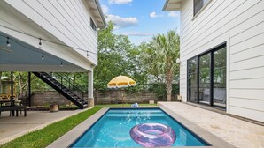 A backyard with a swimming pool, a covered patio, and a staircase leading to a deck. - East Austin + Private Pool - Eastside Palm Combo! (Austin)