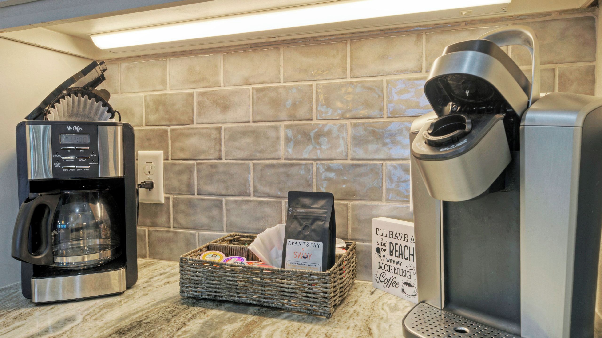 Una cafetera, una cesta con cápsulas de café y un cartel en la pared.