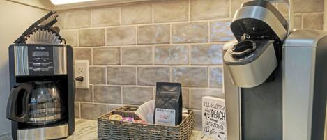 A coffee machine, a basket with coffee pods, and a sign on the wall.
