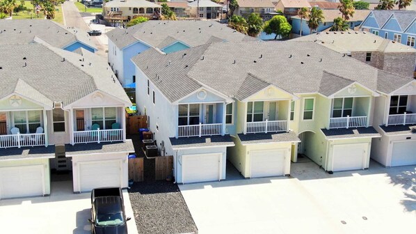 A row of beach houses with individual garages, a small pool, and a clear view of the ocean. - Peaceful Paradise Private Pool, Balcony Views + 5 Mins to Whitecap Beach (Corpus Christi)