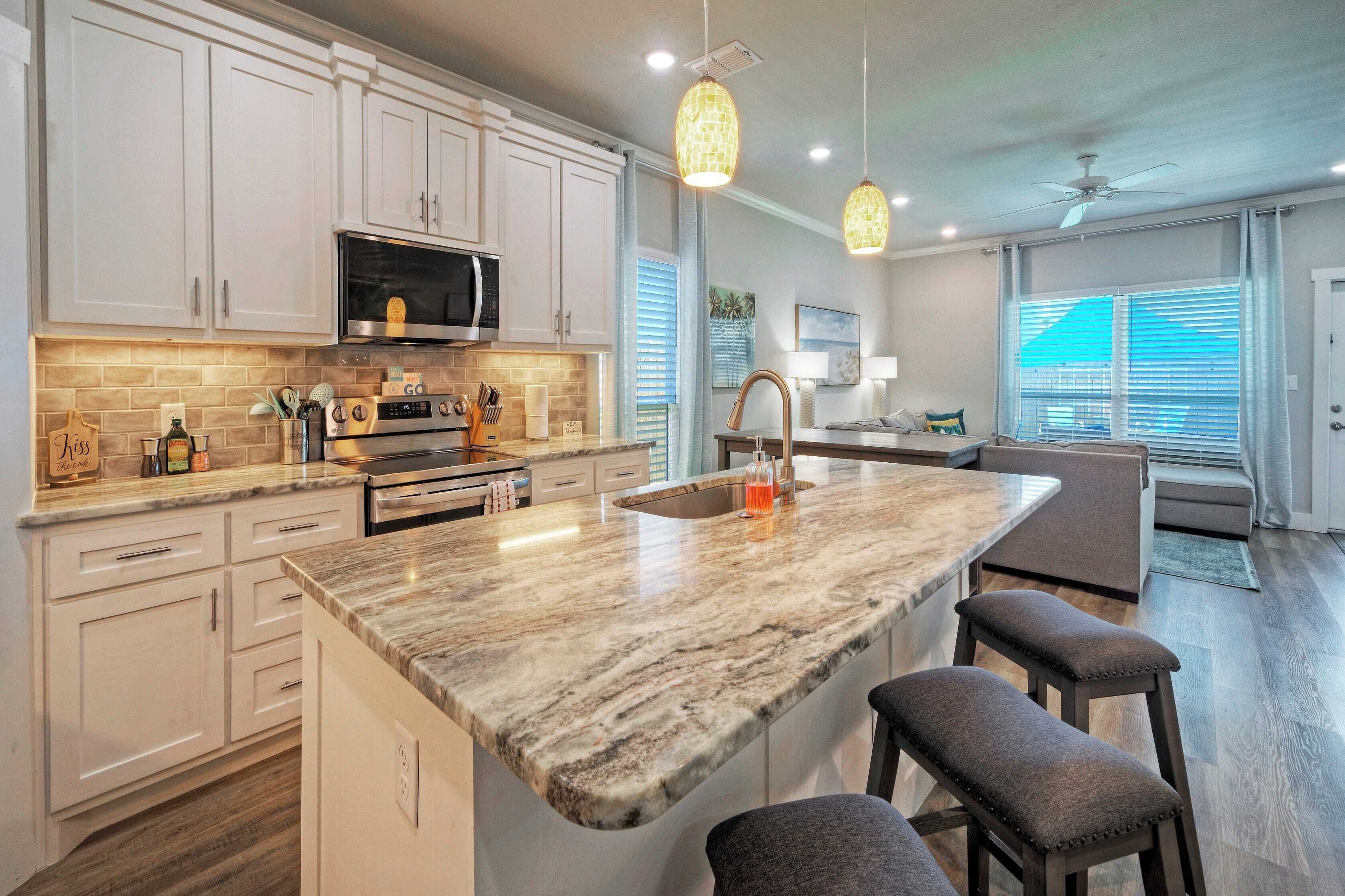 A modern kitchen with white cabinets, a granite countertop, and pendant lighting.