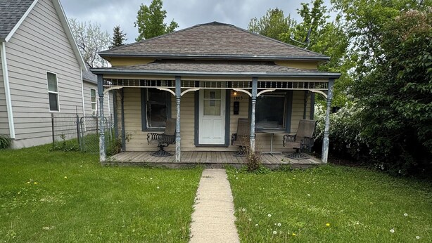 Une maison à deux étages avec un porche, une pelouse devant et un trottoir menant à la porte d’entrée.