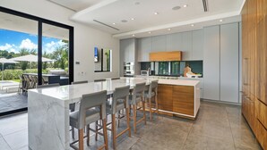 A modern kitchen with a marble island, grey cabinets, and a wooden countertop.