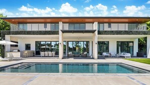 A modern house with a swimming pool, outdoor seating, and a covered patio area.
