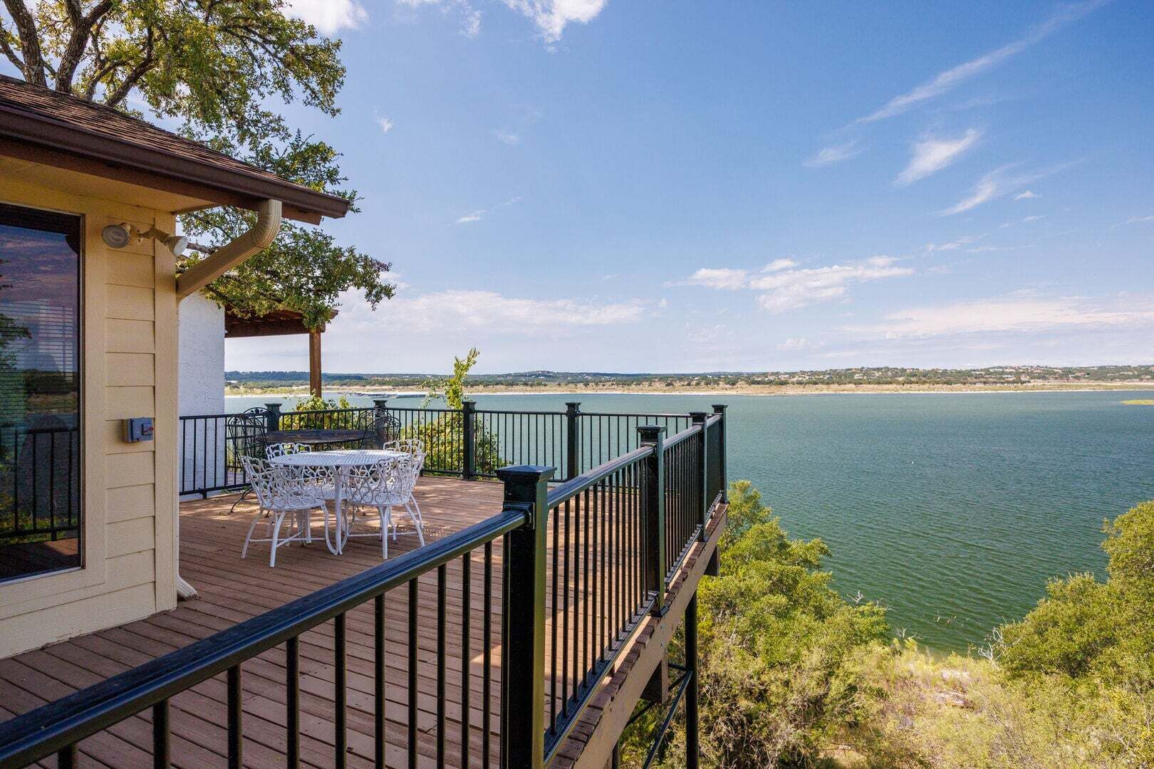 A deck with outdoor furniture overlooking a lake.