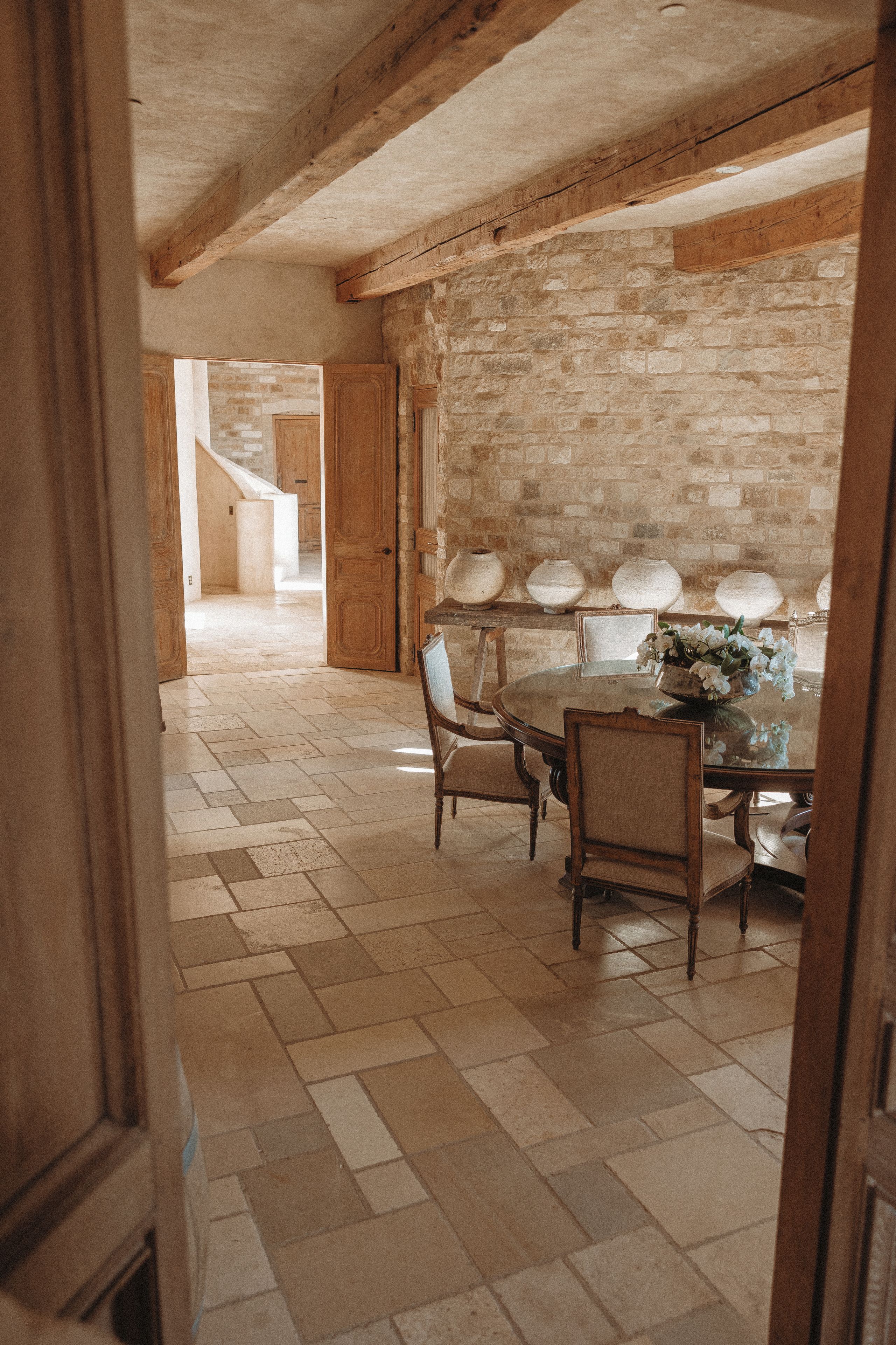 A rustic dining room with a stone wall, wooden furniture, and a tiled floor.