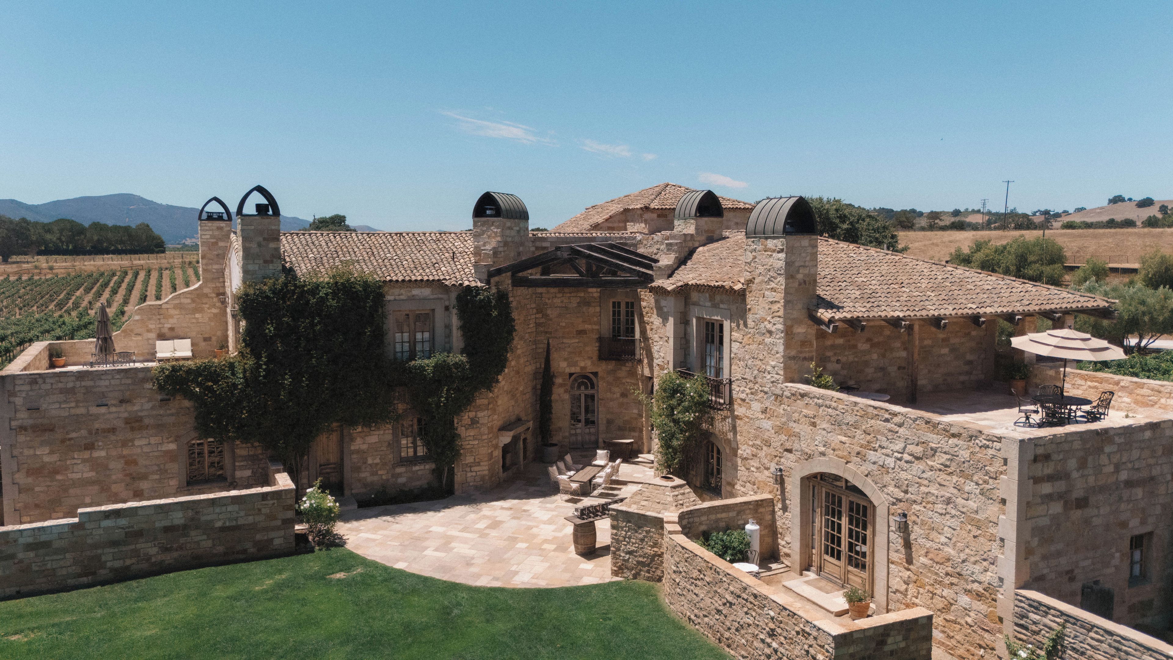 A stone building with a courtyard, a pergola, and a view of the surrounding landscape.