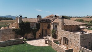 A stone building with a courtyard, a pergola, and a view of the surrounding landscape.