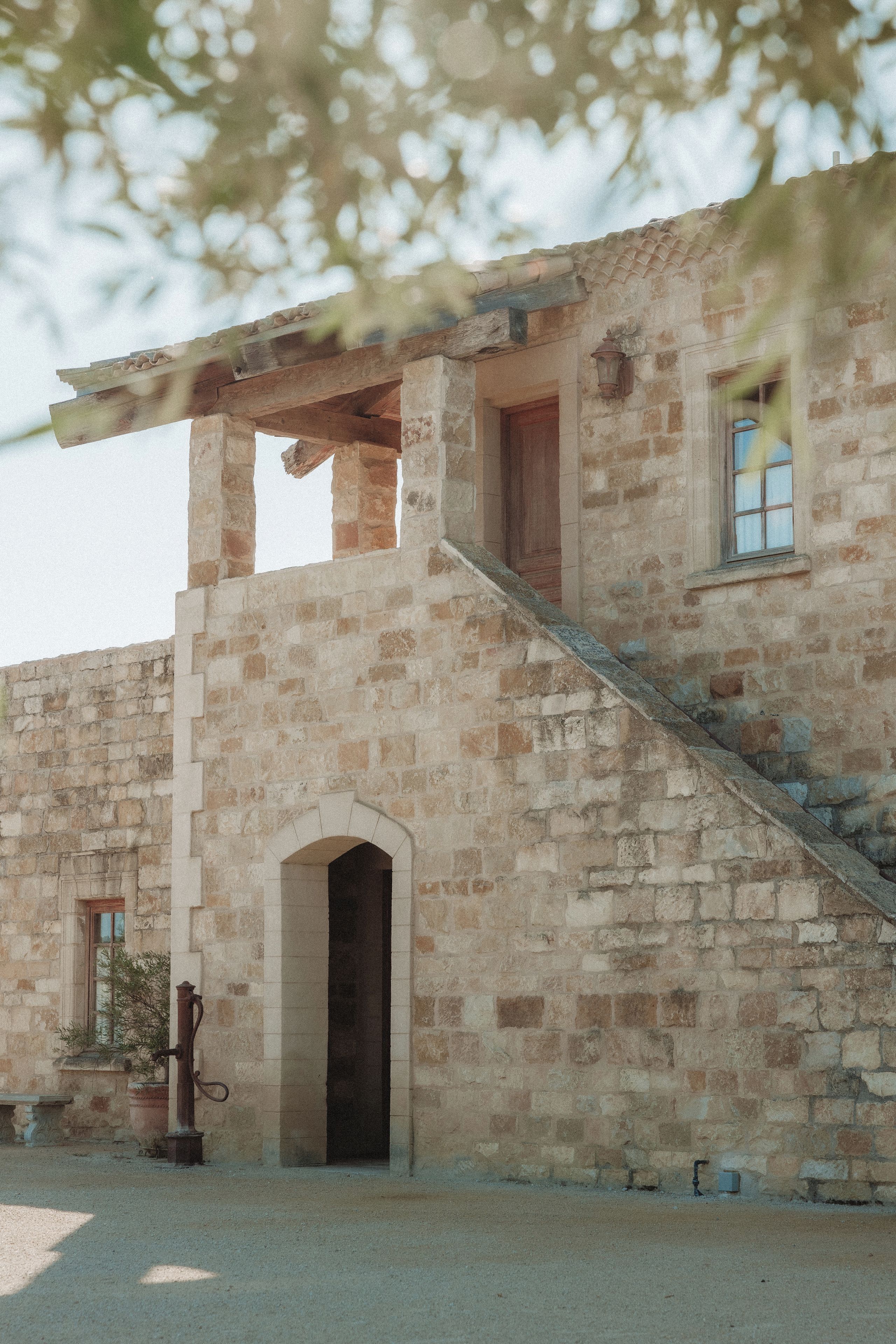 Un edificio de piedra con una escalera de madera que conduce a un arco de entrada.