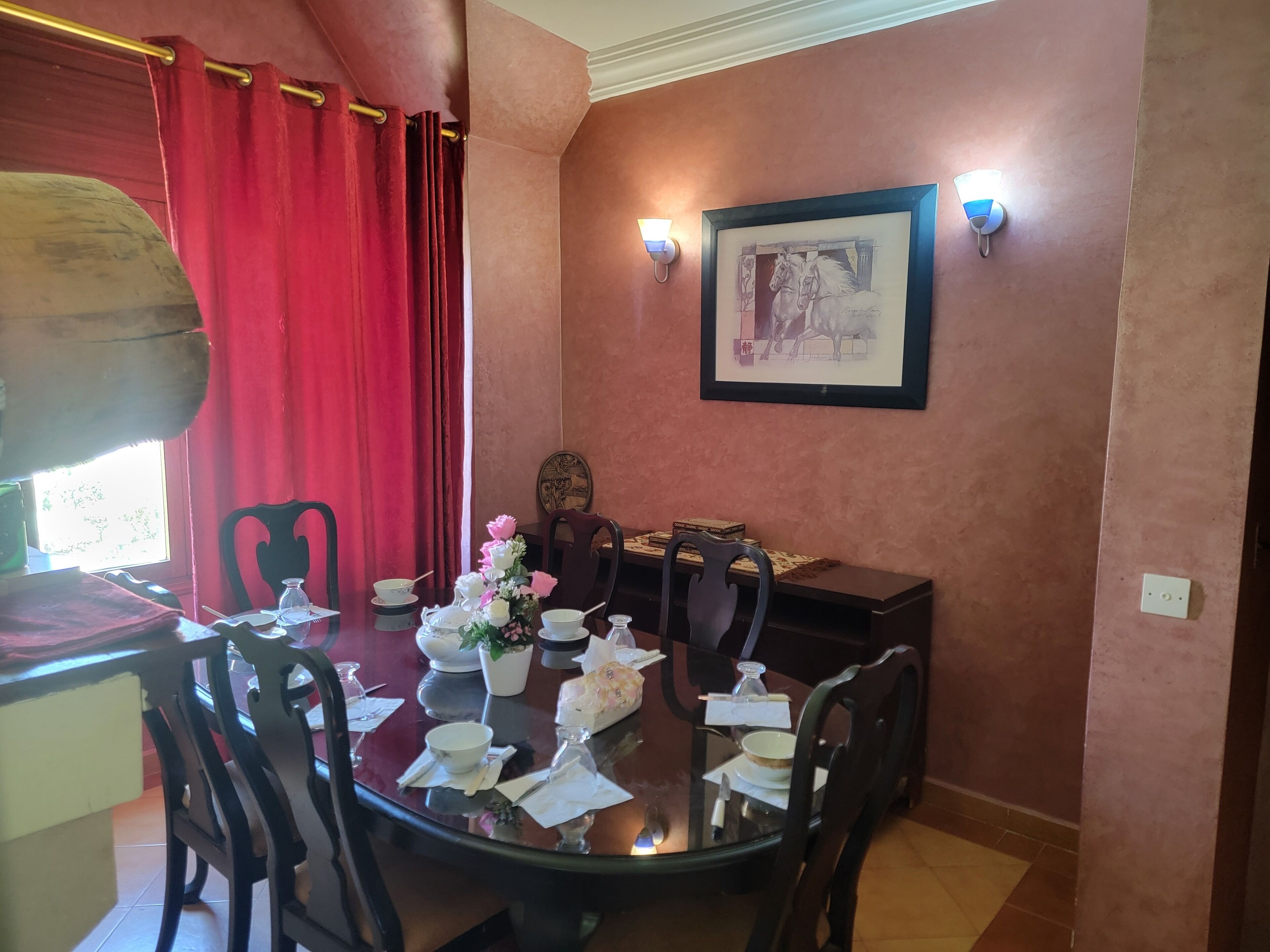 Un comedor con una mesa redonda, sillas y una cortina roja.