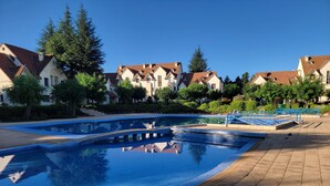Una piscina con plataforma de baldosas, rodeada de edificios residenciales con tejados rojos.