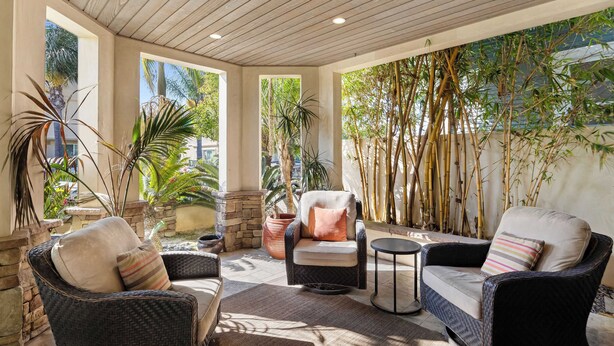A sunlit patio with wicker furniture, stone accents, and bamboo plants.