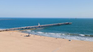 A beach with a pier extending into the ocean, sandy beach, and clear blue water. - Seventh & Shore Stylish Seal Beach Home w/ Elevator, Fireplace + Bold Design (Seal Beach)
