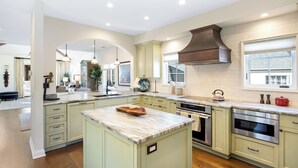 A modern kitchen with a large island, built-in appliances, and a window providing natural light.