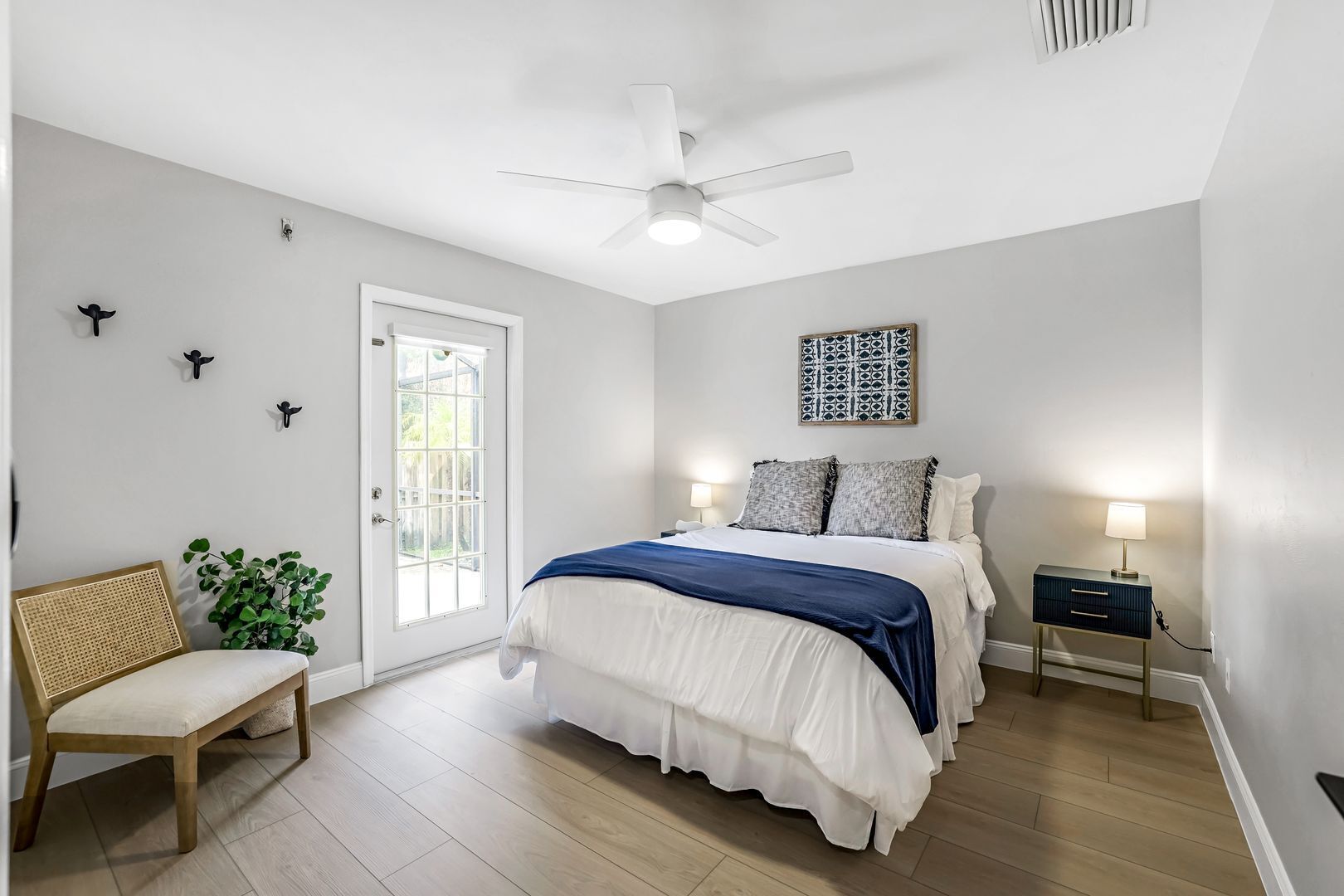 A bedroom with a bed, bedside table, lamp, chair, and a window with a view.