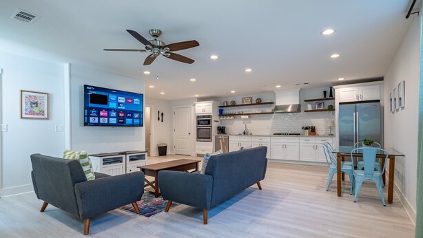 A modern living room with a flat-screen TV, grey sofas, a wooden coffee table, and a ceiling fan. - Upscale 2BR Apartment Near Emory Hospital and CDC (Atlanta)